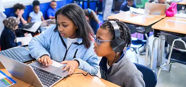 girl and boy looking at a laptop in a classroom